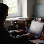 Solo agency owner working on laptop at desk with clean automated workflow setup