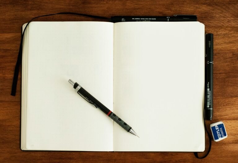 Two physical notebooks open on a wooden table with a pen for analog task management